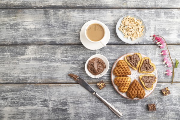 Homemade waffle with chocolate butter and cup of coffee on a gray wooden background. top view, flat lay, copy space