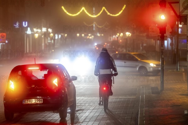 Cyclist, darkness, inner city traffic, Rüttenscheider Straße, bicycle lane, fog, autumn, winter, evening traffic, North Rhine-Westphalia, Germany, Europe