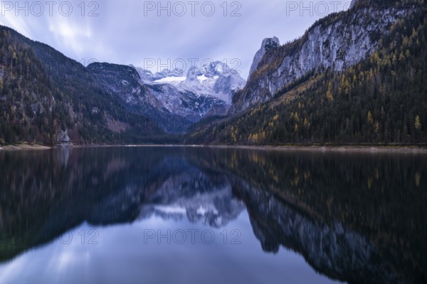 The Vordere Gosausee lake in autumn with a view of the Dachstein mountain range. The Gosaukamm on the right. Cloudy sky. Reflection. Long exposure. Vorderer Gosausee, Gosau, Gosau valley, Salzkammergut, Upper Austria, Austria, Europe