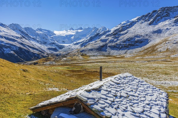 Alpine hut with snow-covered roof, slightly snow-covered alpine meadow, behind the Moiry glacier, near Grimentz, Val d'Anniviers, Valais Alps, Canton Valais, Switzerland, Europe