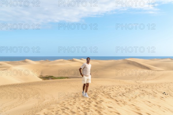 Tourist exploring the scenic landscape of maspalomas dunes with the ocean in the background