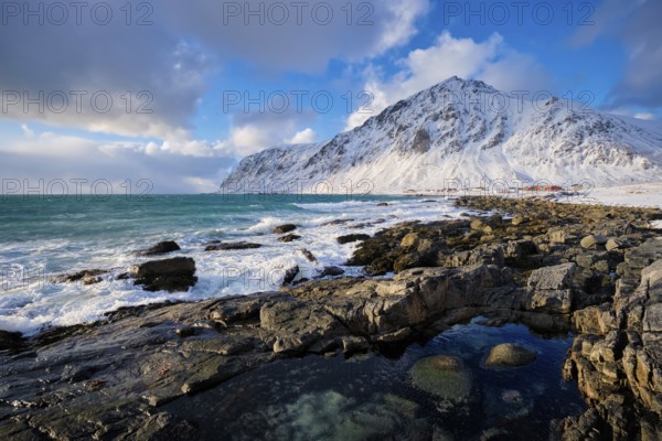 Beach of Norwegian sea on rocky coast in fjord on sunset in winter. Vareid beach, Lofoten islands, Norway, Europe