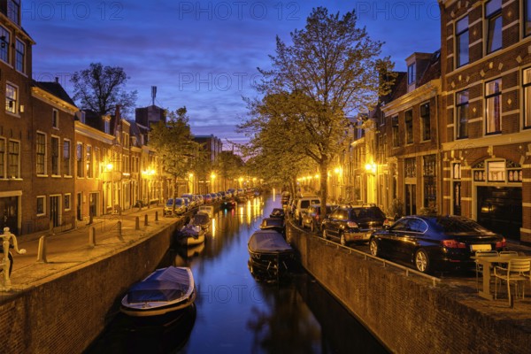 Typical Netherlands city view, canal with boats and houses illuminated in the evening. Haarlem, Netherlands