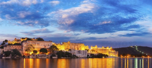 Panorama of famous romantic luxury Rajasthan indian tourist landmark, Udaipur City Palace in the evening twilight with dramatic sky, panoramic view. Udaipur, India, Asia
