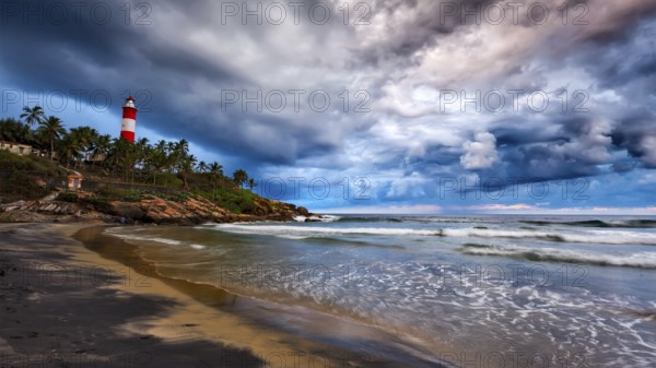 Panorama of gathering storm on beach and Kovalam (Vizhinjam) lighthouse on stormy sunset. Kerala, India, Asia