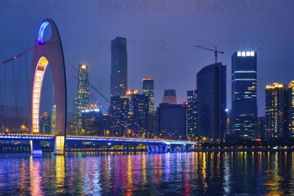 Guangzhou cityscape skyline over the Pearl River with Liede Bridge illuminated in the evening. Guangzhou, China, Asia