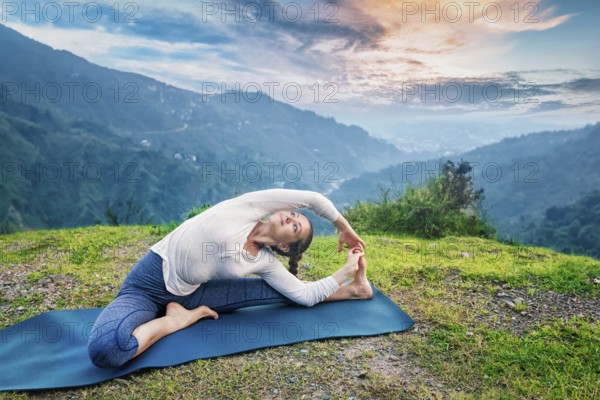 Yoga outdoors, young sporty fit woman doing Hatha Yoga asana parivritta janu sirsasana, Revolved Head-to-Knee Pose, in