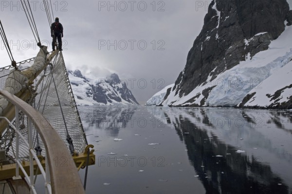 Sailing ship with man on bowsprit looking into the Lemaire Channel, Kodak Gap, Antarctica