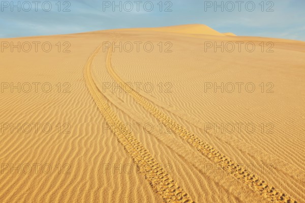 All-terrain vehicle (ATV) tracks in white sand dunes on sunrise, Mui Ne, Vietnam. Dunes around Bao Trang (White Lake near Phan Thiet) are a major tourist attraction at Mui Ne