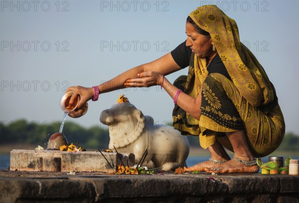 MAHESHWAR, INDIA, APRIL 26: Indian woman performs morning pooja on sacred river Narmada ghats on April 26, 2011 in Maheshwar, Madhya Pradesh, India. To Hindus Narmada is one of 5 holy rivers of India