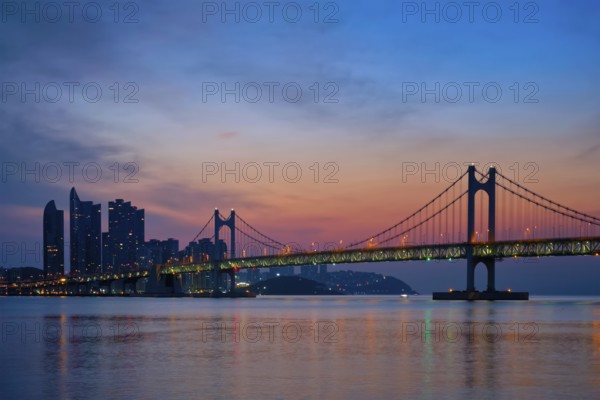 Gwangan Bridge on sunrise with skyscrapers and dramatic sky. Busan, South Korea, Asia
