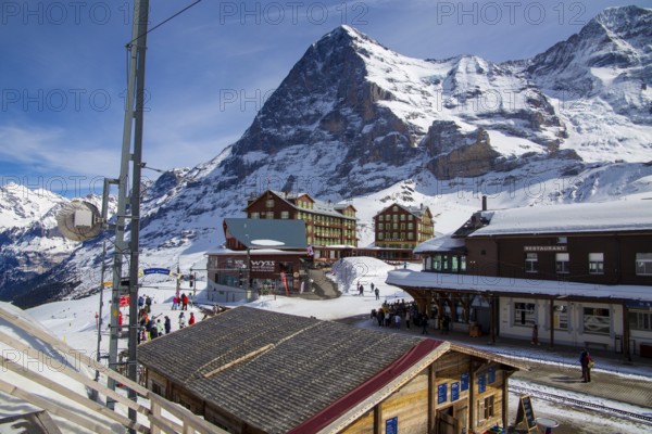 25 March 2024, Kleine Scheidegg, Grindelwald Switzerland : Many skiers and tourists enjoy the sunny winter weather. The famous north face of the Eiger in the background