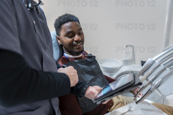Dentist showing a dental x ray on a tablet to a smiling patient during a consultation in a modern dental clinic