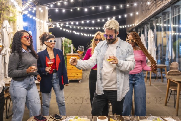 Cool man dancing with multiracial woman at night party in the roof of a bar at city