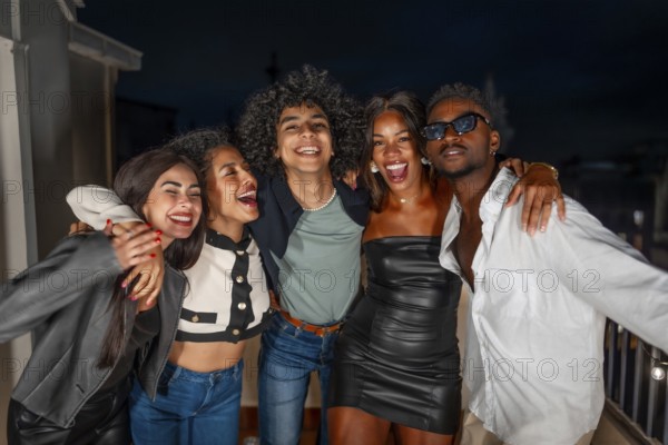 Portrait of multi-ethnic group of males and females friends embracing from the shoulder partying at night