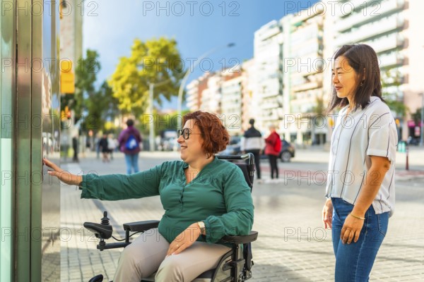 Disabled woman in a wheelchair and Asian friend waiting for the public transport elevator