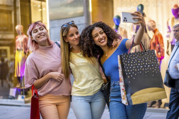 Three multi-ethnic diverse young women taking selfie carrying shopping bags in a mall