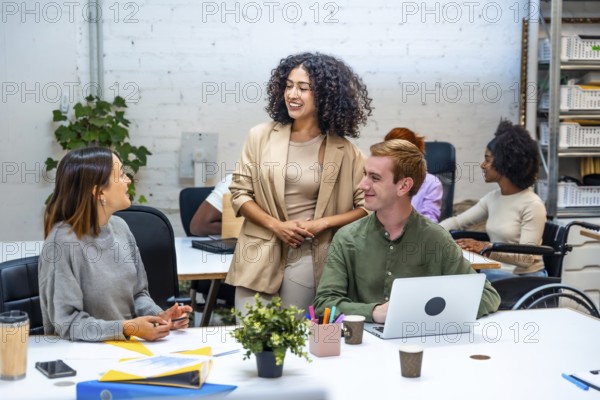Three diverse females and male coworkers talking distracted in a modern coworking room