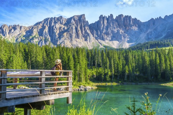 Female tourist admiring the stunning landscape of lake carezza with the latemar massif in the background, a popular destination in the italian dolomites