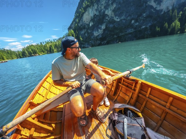 Tourists enjoying a sunny day rowing on the famous lake braies, surrounded by the stunning landscape of the dolomites