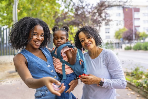 Portrait of three generation african female family in the park smiling at camera standing together