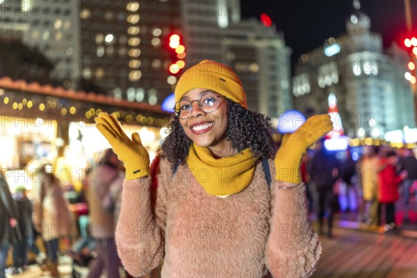 Young woman wearing yellow winter clothes enjoying christmas market in plaza de espana, madrid, at night