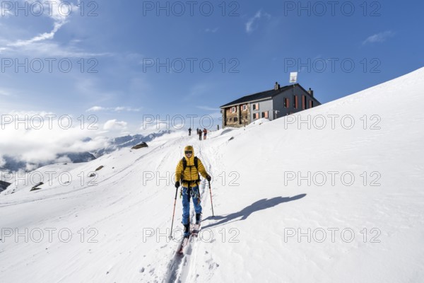 Ski tourers in front of the Chamanna d'Es-cha mountain hut in a wintry mountain landscape, Bündner Haute Route ski tour, Albula Alps, Rhaetian Alps, Grisons, Eastern Switzerland, Switzerland, Europe
