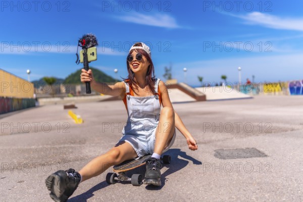 Smiling chinese female vlogger filming at skateboard park in summer