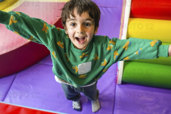 Preschooler enjoying playtime in colorful indoor playground, expressing pure happiness and excitement