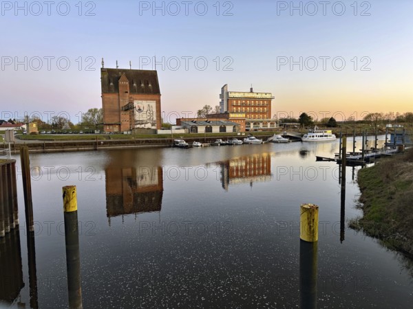 Harbour view at sunset with reflecting buildings on calm water, old warehouses, hotel, Elbe, Dömitz, Mecklenburg-Vorpommern, germany