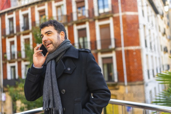Adult caucasian man in elegant warm clothes talking to the mobile standing in the city