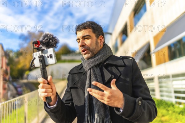 Adult male vlogger in elegant winter clothes recording online video in the city