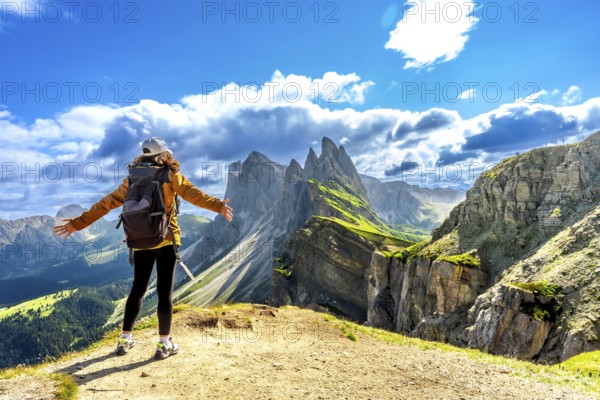 Hiker with open arms enjoying the breathtaking view of the odle mountains in seceda, dolomites, italy
