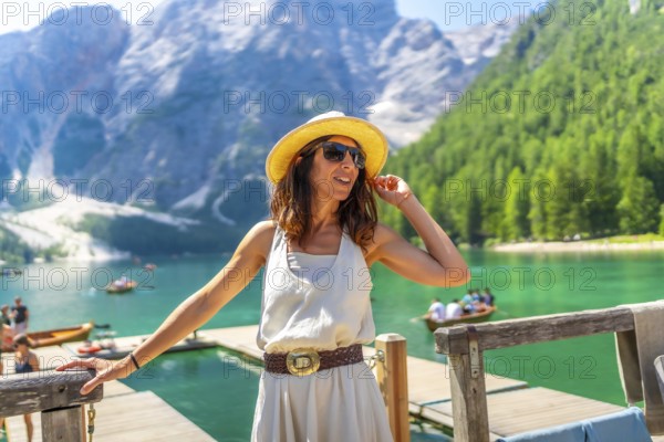 Fashionable tourist wearing sunglasses and straw hat enjoying summer at lake braies, also called pragser wildsee, in the dolomites, italy