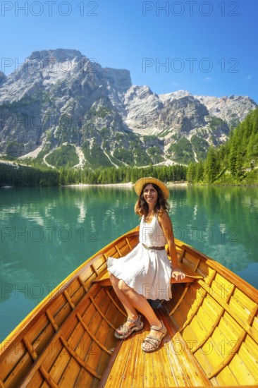 Young woman relaxing on a wooden rowboat, enjoying the breathtaking scenery of lake braies and the surrounding dolomites