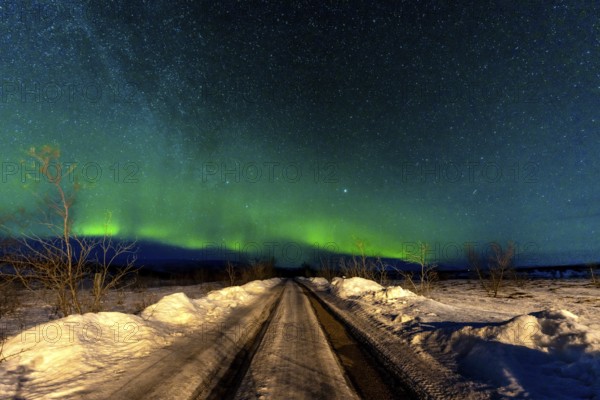 A beautiful Northern Lights in the cold Icelandic winter at night on a snowy trail. Aurora Borealis concept