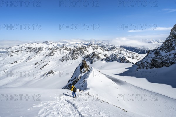 Mountaineer with ice axe and crampons, ascent through steep snowfield to Piz Kesch or Piz d'Es-cha in winter, view of mountain panorama with Vadret da Porchabella glacier, Albula Alps, Rhaetian Alps, Grisons, Eastern Switzerland, Switzerland, Europe