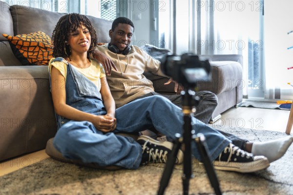 Two influencers are recording a vlog in their living room, creating engaging content for their online audience