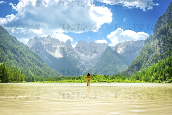 Woman standing in the water enjoying a summer swim in the beautiful lago di landro with the dolomites in the background