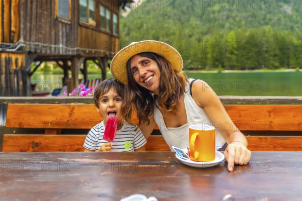 Tourists enjoying a summer day with ice cream and coffee by a mountain lake in the italian alps