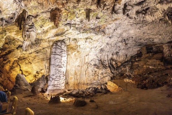 Tourists riding a train admiring the illuminated stalagmites and stalactites inside the famous postojna cave, a popular destination in slovenia