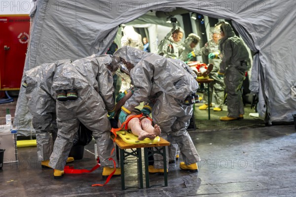 Decontamination of injured persons after an assumed accident involving hazardous substances, fire brigade and aid organisations practise setting up and operating a decontamination station, injured persons are sighted and then washed in a special shower tent to remove possible hazardous substances and chemicals in order to avoid further injuries, the emergency services wear special, ventilated protective suits, large-scale exercise by the Essen fire brigade