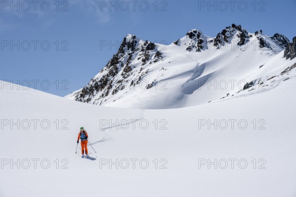 Ski tourer on the descent, minimalist winter landscape, white snow and dark mountains on the Scalettahorn, Graubünden, Switzerland, Europe