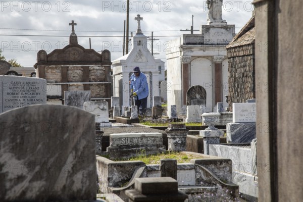 New Orleans, Louisiana - A groundskeeper at work in St. Joseph Cemetery #1, established in 1854. Burial in New Orleans is generally above ground due to the city's high water table and its location below sea level
