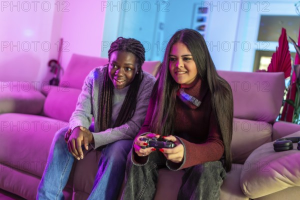 Two friends enjoying their free time playing with a gamepad sitting on a sofa in a colorful living room