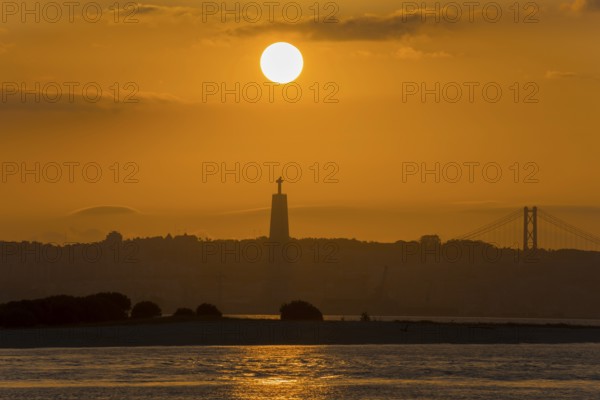 Atmospheric scene with a sunset over a statue and a bridge bathing the water in golden light, Statue Cristo Rei, Ponte 25 de Abril, Bridge of 25 April, Suspension bridge over the Tagus, Lisbon, Lisboa, Portugal, Europe
