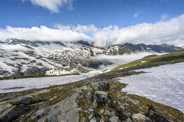 Mountain landscape with snowfields and high fog in the valley, behind summit Hoher Weißzint and Hochsteller with glacier Schlegeiskees, Berliner Höhenweg, Zillertal Alps, Tyrol, Austria, Europe