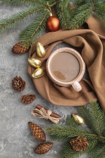 Christmas or New Year composition. Decorations, cones, cinnamon, fir and spruce branches, cup of coffee, wool scarf on a gray concrete background. Top view, close up, flat lay