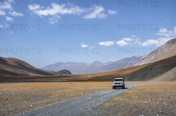 Off-road vehicle on gravel track, Burkhan mountain valley with meandering river, barren dramatic mountain landscape, Terskey Ala-Too, Tien Shan, Issyk Kul province, Kyrgyzstan, Asia
