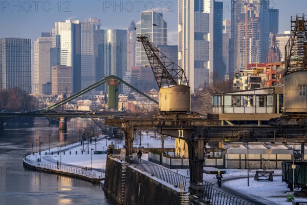 The skyline of Frankfurt am Main, skyscrapers of the banking district, historic harbour cranes at the Wesel shipyard, wintry morning, Hesse, Germany, Europe